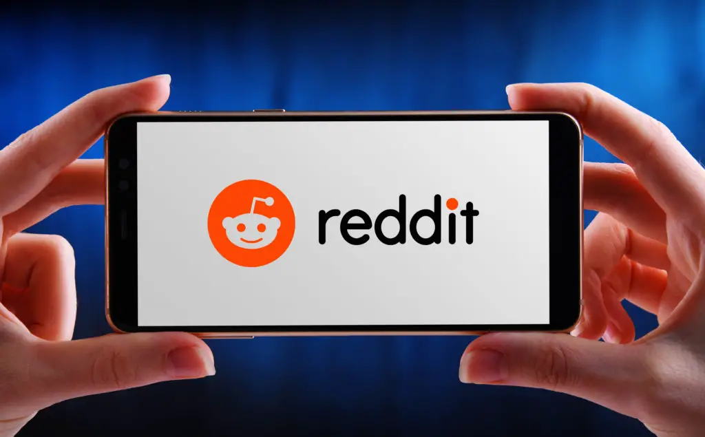 A person holding a phone with displayed Reddit logo