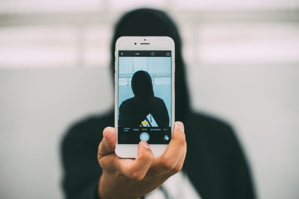 A person with a covered face making a self-portrait photo