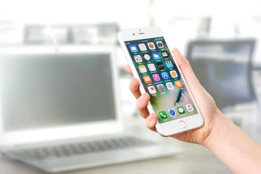 A woman holding a silver iPhone