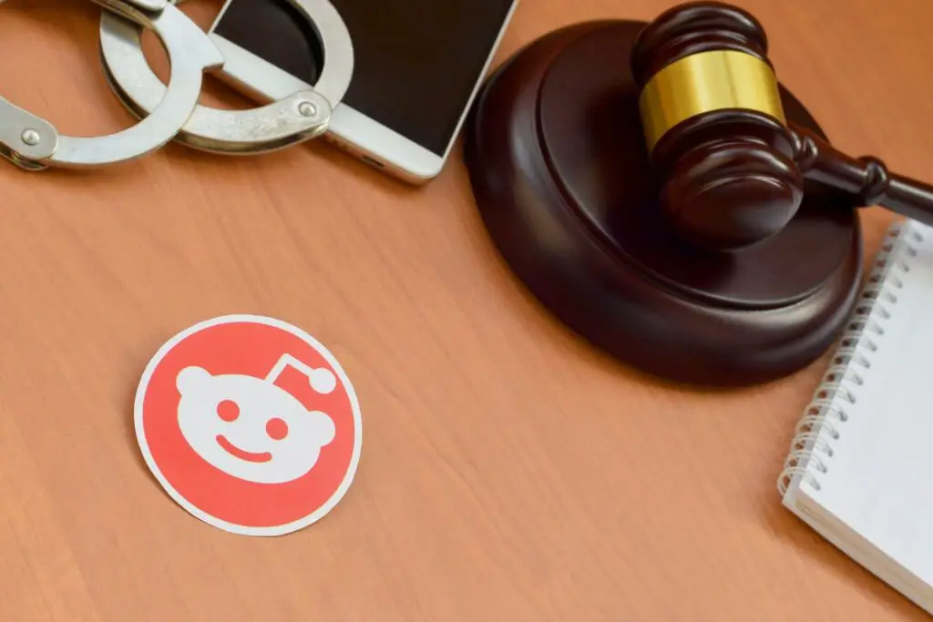 Reddit logo next to handcuffs and a gavel