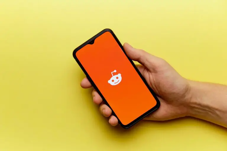 Man holding a smartphone with a Reddit logo