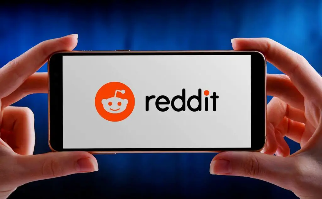 Hands holding a smartphone with Reddit logo