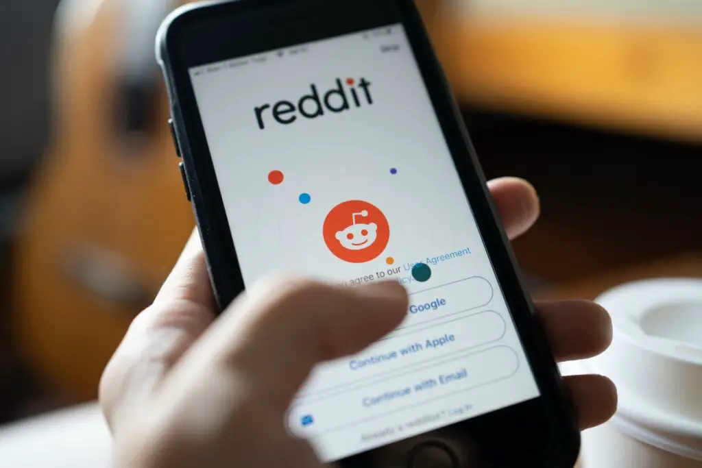 Man holding a smartphone with a Reddit logo